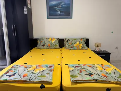 a yellow bed with two pillows on top of it at Mitić Apartmani 1 in Niš