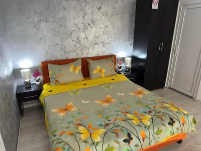 a bedroom with a bed with a yellow and orange blanket at Mitić Apartmani 1 in Niš