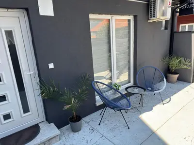 two chairs and a table in front of a building at Mitić Apartmani 1 in Niš