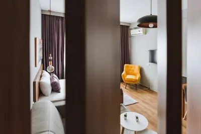 a room with a bed and a yellow chair at Central Plaza Apartments in Niš