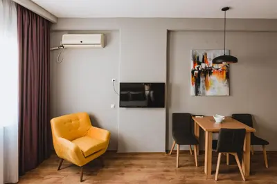a dining room with a yellow chair and a table at Central Plaza Apartments in Niš