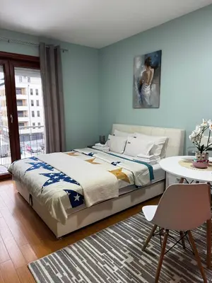 a bedroom with a bed and a table and a table and chair at IWA CENTAR Apartments & Wellness in Vrnjačka Banja