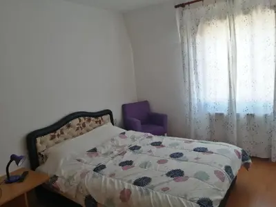 a bedroom with a bed and a purple chair at Ćele-kula Apartment in Niš