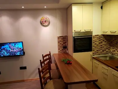 a kitchen with a table and a tv on a wall at Apartment Superior Centar in Kopaonik