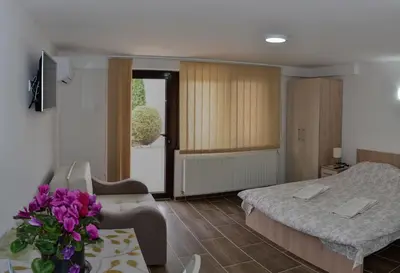 a hotel room with two beds and a table with flowers at Apartmani Janja in Soko Banja