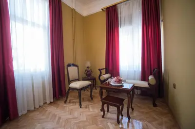a living room with red curtains and a table and chairs at Center Deluxe Garni Hotel in Niš