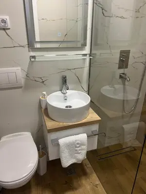 a bathroom with a white sink and a toilet at Center Deluxe Garni Hotel in Niš