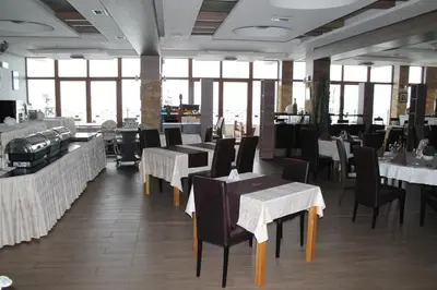 a dining room with tables and chairs and windows at Lux Apartment Milmari Reko Premier 14 Kopaonik in Kopaonik
