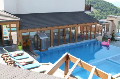 a pool with chairs and a house with a swimming pool at Lux Apartment Milmari Reko Premier 14 Kopaonik in Kopaonik