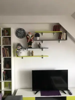 a living room with a tv and a clock and shelves at Apartman Biblioteka Čardaka 10/61 in Kopaonik