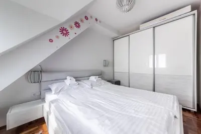 a bedroom with a white bed with flowers on the wall at Apartman Biblioteka Čardaka 10/61 in Kopaonik