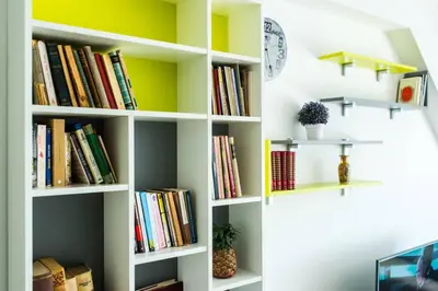 a book shelf filled with books and a clock at Apartman Biblioteka Čardaka 10/61 in Kopaonik