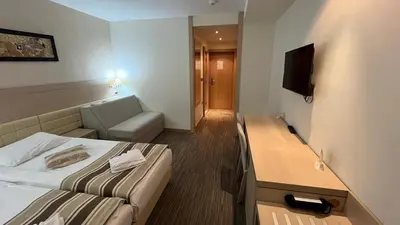 a small hotel room with a bed and a desk at Angella Konaci Kopaonik in Kopaonik