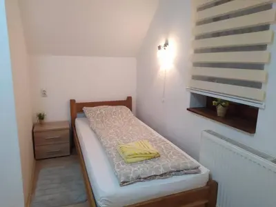 a small bedroom with a bed with a yellow pillow at Vila Žubor in Crni Vrh