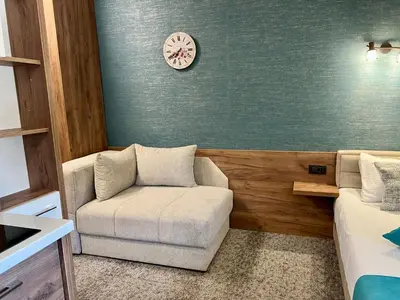 a living room with a chair and a clock on the wall at Select Lux Angella-Konaci in Kopaonik