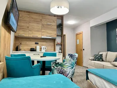 a living room with a table and blue chairs at Select Lux Angella-Konaci in Kopaonik
