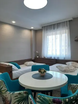 a room with two beds and a table and chairs at Select Lux Angella-Konaci in Kopaonik