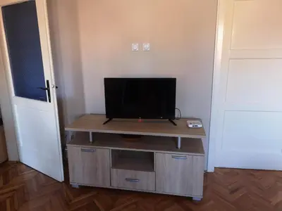 a tv sitting on top of a wooden stand in a room at City Center Apartment JOTIC in Pirot