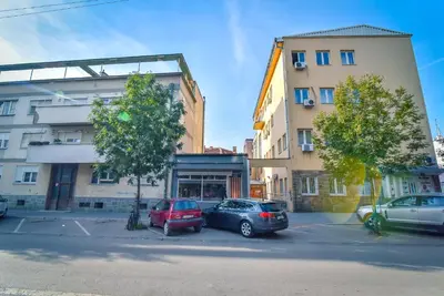 two cars parked in a parking lot in front of buildings at City Center Apartment JOTIC in Pirot