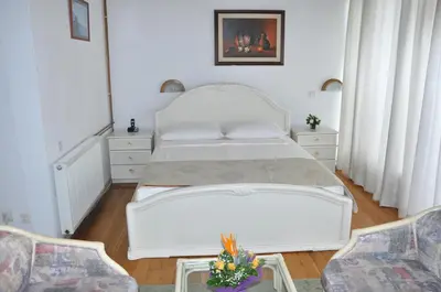 a bedroom with a white bed and two chairs at Hotel Simpo Pržar in Vranje