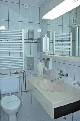 a white bathroom with a sink and a toilet at Hotel Simpo Pržar in Vranje