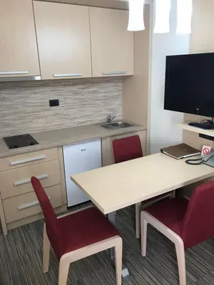 a kitchen with a table and two red chairs at Apartman Konaci Maglic in Kopaonik
