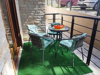 a table and chairs on a balcony with green flooring at Stella Apartments in Vrnjačka Banja