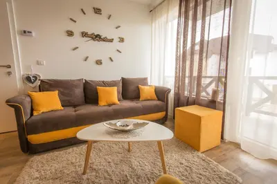 a living room with a couch and a clock on the wall at Family Apartmani Kopaonik in Kopaonik