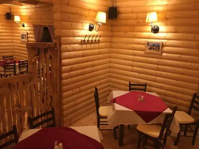 a dining room with two tables and a red umbrella at Župa Apartmani in Kopaonik