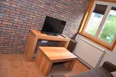 a living room with a tv on a wooden stand at Župa Apartmani in Kopaonik