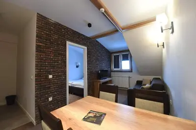 a room with a dining table and a brick wall at Župa Apartmani in Kopaonik