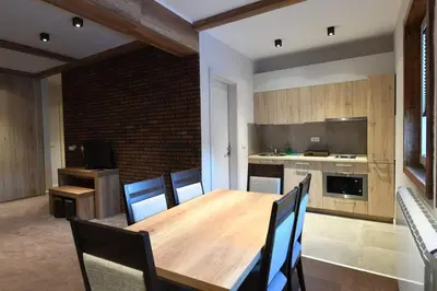 a dining room with a wooden table and a kitchen at Župa Apartmani in Kopaonik