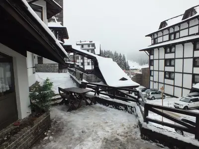 a snow covered balcony of a house with a table at Apartment 102, Vila 