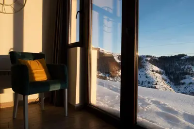 a chair with a yellow pillow sitting in front of a window at Apartments Topview Kopaonik-Dvori in Kopaonik