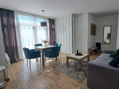 a living room with a table and blue chairs at Apartments Topview Kopaonik-Dvori in Kopaonik