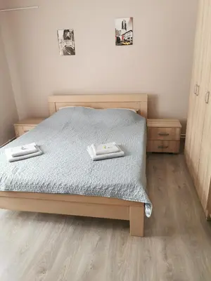 a bedroom with a bed with blue sheets and wooden floors at Apartmani Milica in Kruševac