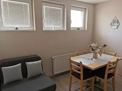 a dining room with a table and chairs and windows at Apartmani Milica in Kruševac