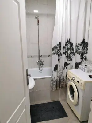 a bathroom with a washing machine and a shower curtain at Apartmani Milica in Kruševac