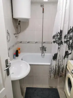 a bathroom with a tub and a sink and a shower curtain at Apartmani Milica in Kruševac