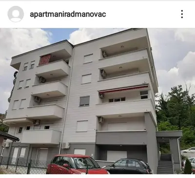 a building with cars parked in front of it at Apartman Radmanovac in Vrnjačka Banja