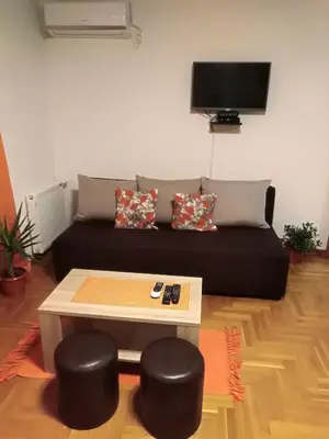 a living room with a couch and a table and stools at Apartman Radmanovac in Vrnjačka Banja