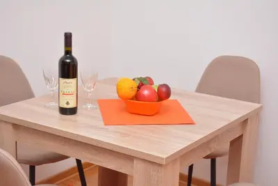 a table with a bottle of wine and a bowl of fruit at Apartman Radmanovac in Vrnjačka Banja