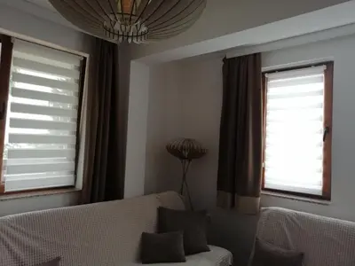 a living room with a couch and two windows at Apartman Košuta, Kopaonik in Kopaonik