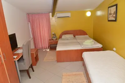 a small room with two beds and a desk and a computer at Apartments Imper - IMD in Niš