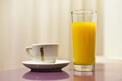 a glass of orange juice next to a cup of coffee at Apartments Imper - IMD in Niš