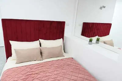 a bedroom with a bed with a red headboard at Apartments Imper - IMD in Niš