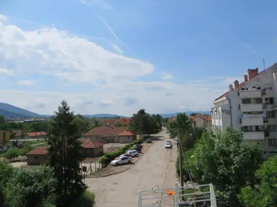 a street in a town with cars parked on the road at Bisa in Soko Banja