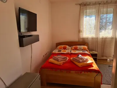 a bedroom with a bed with red sheets and a flat screen tv at Bisa in Soko Banja