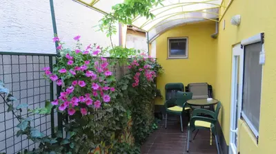 a patio with pink flowers and a table and chairs at Guest House Pavlovic in Soko Banja