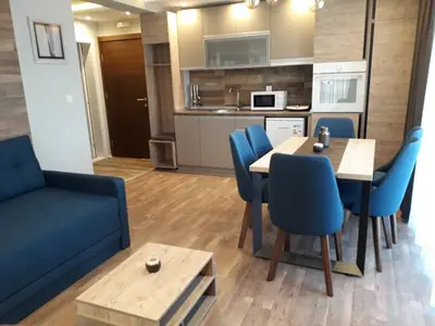 a living room with a dining table and blue chairs at Apartman Lux Kopaonik in Kopaonik